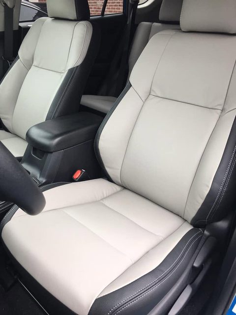 Front seats in light gray leather with black sides and white stitching
