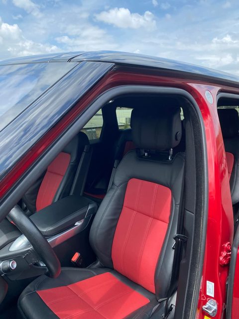 Driver seat in black leather with red centers, seen through the open door of a red SUV